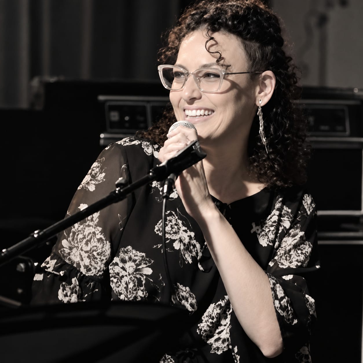 מירי וקסלר, מורה לפיתוח קול בצריף, שרה עם מיקרופון על הבמה